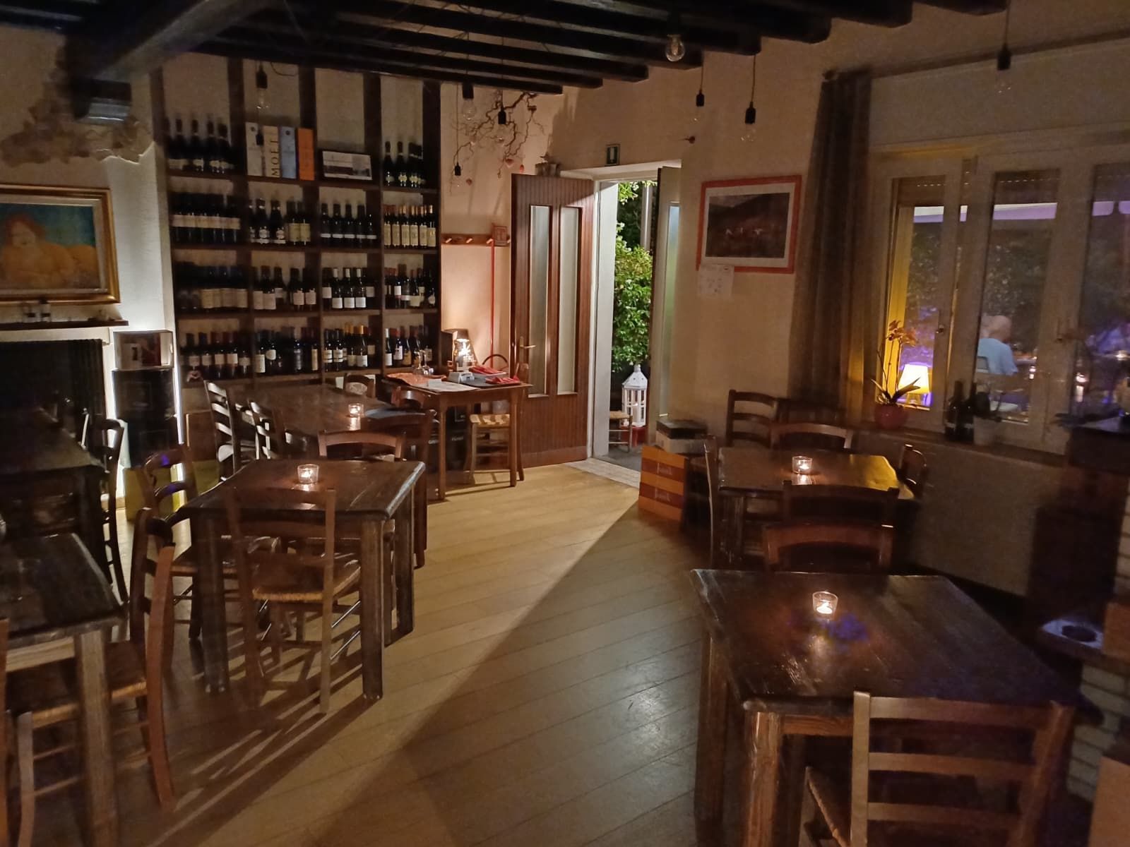 Sala interna con tavoli in legno e parete delle bottiglie
