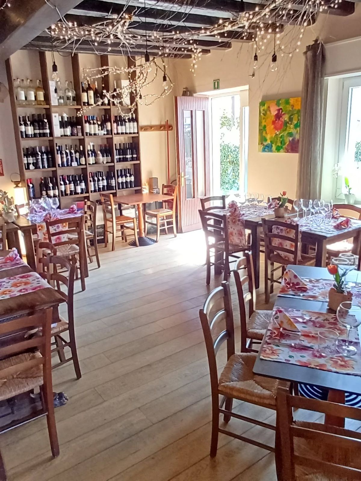 La sala luminosa con tavoli in legno e scaffali di vini